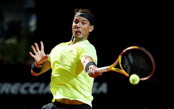 Rafael Nadal in a powerful forehand motion at a major tennis tournament.